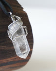Right angle close-up of clear quartz point necklace for men – detailed white gold copper wire wrapping, natural quartz crystal, black leather cord.