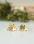 Close-up of raw unpolished citrine crystals on stud earrings showing natural golden color and organic texture