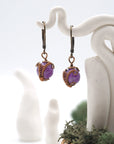 Close-up of handcrafted amethyst drop earrings with antique bronze copper wire wrapping.