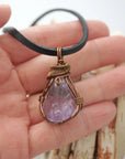 Handmade amethyst mens pendant held in hand showing size — natural polished-raw amethyst stone wire wrapped in bronze copper finish, 40-60 carats, one of a kind