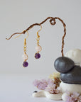 Zoomed out view of minimalist amethyst and rose quartz dangle earrings in gold plated copper with fish hook ear wires