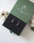 Amethyst sterling silver drop earrings in branded Designs by Nature Gems jewelry box, showcasing handcrafted faceted amethyst and sterling silver wire wrapping