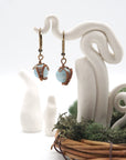 Front angle of aquamarine drop earrings hanging on a jewelry display, wire-wrapped design.