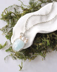 Handmade silver wire wrapped aquamarine and freshwater pearl necklace laying flat on a silver plated chain, artisan jewelry for women