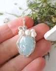 Aquamarine and freshwater pearl pendant necklace in hand for size reference, silver wire wrapped, handcrafted gemstone jewelry