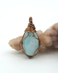 Close-up of aquamarine pendant front, polished gemstone in simple artisan antique bronze wire wrapping