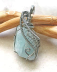 Side view of raw aquamarine pendant showing detailed artisan wire wrapping in dark silver