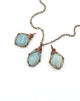 Three aquamarine pendants showing natural variation in size, shape, and blue color with antique bronze wire wrapping