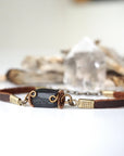Close-up of natural black tourmaline hand wire-wrapped in antique bronze on a brown leather band