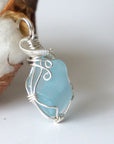 Angled view of the sterling silver bail and wire wrap on a blue topaz pendant