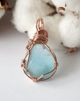 Back of a blue topaz pendant showing the hand wire-wrapped rose gold filled pattern
