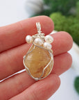 Citrine and freshwater pearl pendant necklace in hand for size reference, silver wire wrapped, handcrafted gemstone jewelry