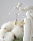 Side view of citrine sterling silver drop earrings showing wire wrapped natural faceted citrine, artisan craftsmanship, on a display – Designs by Nature Gems