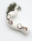 Bird’s eye view of clear quartz drop earrings laying flat on a display, showing detailed wire wrapping and gemstone clarity.