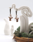 Front angle of clear quartz drop earrings hanging on a jewelry display, wire-wrapped design.