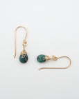 Closeup showing details of emerald drop earrings, faceted emerald stone, 14k gold filled setting