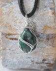 Back view of emerald necklace for men showing detailed sterling silver wire wrapping and natural emerald pendant.