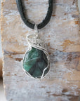 Detailed view of emerald necklace for men with natural polished-raw emerald and 925 sterling silver wire wrapping.