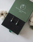 Emerald sterling silver drop earrings in branded Designs by Nature Gems jewelry box, showcasing handcrafted faceted emerald and sterling silver wire wrapping