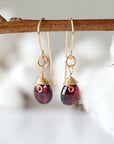 Front view of faceted garnet 14k gold filled drop earrings on display stand, handmade January birthstone dangle earrings