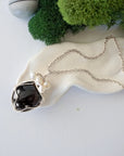 Handmade silver wire wrapped garnet and freshwater pearl necklace laying flat on a silver plated chain, artisan jewelry for women