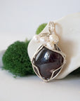 Side angle of handmade garnet and freshwater pearl pendant necklace, silver wire wrapped jewelry