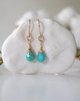 Gold turquoise drop earrings with wire wrapped crystal beads hanging on display, front view showing detailed craftsmanship