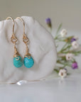 Right side view of gold turquoise drop earrings on display showing wire wrapping detail and natural crystal facets