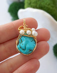 Turquoise and pearl pendant held in hand showing size of wire wrapped gold necklace for women