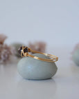 Side view of dainty garnet ring showing minimalist gold wire wrap and polished garnet bead