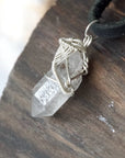 Left angle view of handmade Herkimer diamond pendant for men highlighting sterling silver wire artistry.