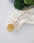 Handmade silver wire wrapped citrine and freshwater pearl necklace laying flat on a silver plated chain, artisan jewelry for women
