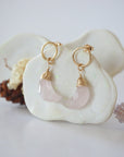 Side angle view of Rose Quartz Moon Open Circle Stud Earrings hanging on jewelry display, minimalist 14k gold filled wire wrap, limited edition.