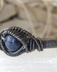 Front view of men's natural 8mm sapphire ring focused on the stone and antiqued 925 sterling silver wire wrapping