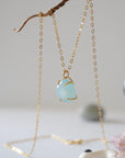 Side angle of minimalist aquamarine necklace in gold, showing polished gemstone in claw setting, 14k gold vermeil