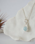 Side angle of minimalist aquamarine necklace, showing soft silver finish wire wrapping and natural aquamarine bead
