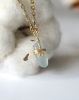 Right side angle of minimalist aquamarine necklace, showing genuine aquamarine pendant and warm gold finish over copper wire