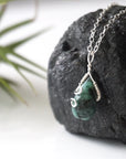 Left angle detail of emerald necklace for women with natural faceted emerald and artisan sterling silver wire wrapping