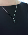 Minimalist emerald necklace for women worn on female model with natural faceted emerald in sterling silver