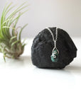 Zoomed out view of minimalist emerald necklace for women with faceted teardrop emerald on sterling silver chain