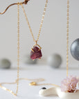 Close front view of minimalist raw garnet pendant in 14k gold vermeil claw setting on a 14k gold filled chain
