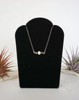 Peridot and freshwater pearl bar necklace in 925 sterling silver on jewelry display, front view