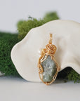 Back angle detail of peridot and freshwater pearl pendant, showing wire wrapping and natural stone