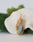 Back angle detail of peridot and freshwater pearl pendant, showing wire wrapping and natural stone