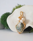 Side angle detail of peridot and freshwater pearl pendant, gold wire wrapped, ethical artisan necklace