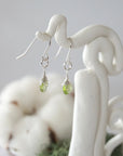 Side view of peridot sterling silver drop earrings showing wire wrapped natural faceted peridot, artisan craftsmanship, on a display – Designs by Nature Gems