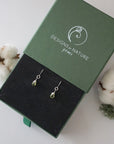 Peridot sterling silver drop earrings in branded Designs by Nature Gems jewelry box, showcasing handcrafted faceted peridot and sterling silver wire wrapping