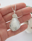 Rainbow moonstone necklace for women shown in hand for size reference with soft silver wire wrapped June birthstone pendant
