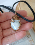 Rainbow moonstone pendant shown in hand for size reference with mixed metal artisan wire wrapping for men