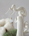 Side view of rainbow moonstone sterling silver drop earrings showing wire wrapped natural faceted rainbow moonstone, artisan craftsmanship, on a display – Designs by Nature Gems